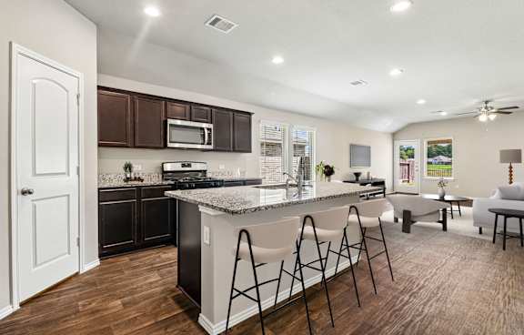 A modern kitchen with dark brown cabinets and a white island.