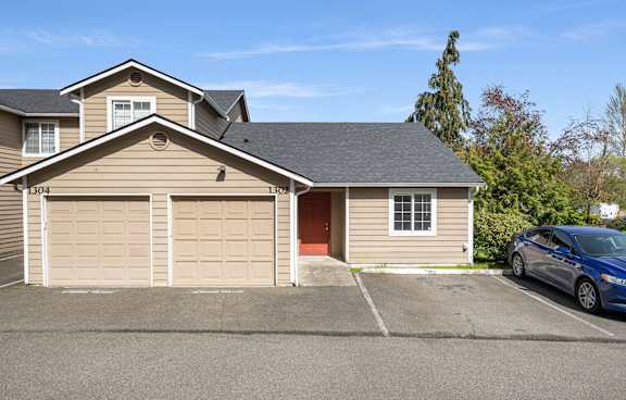 A two-story house with a garage and a car parked in front.