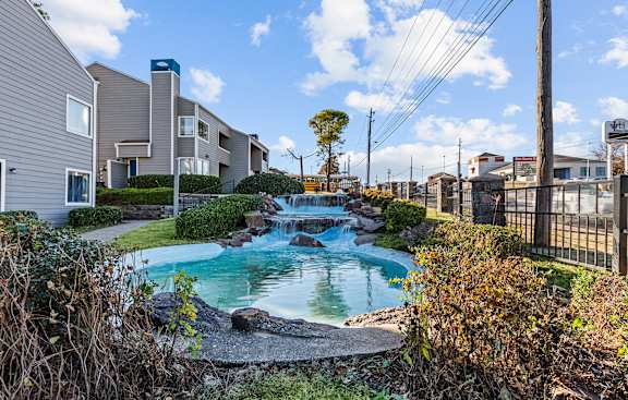 a small pool with waterfalls in front of apartment buildings