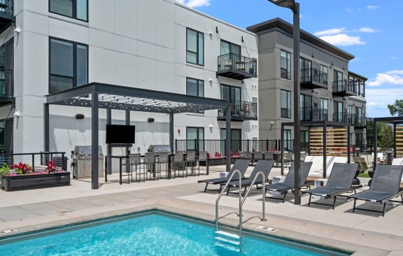 a swimming pool with lounge chairs next to a building
