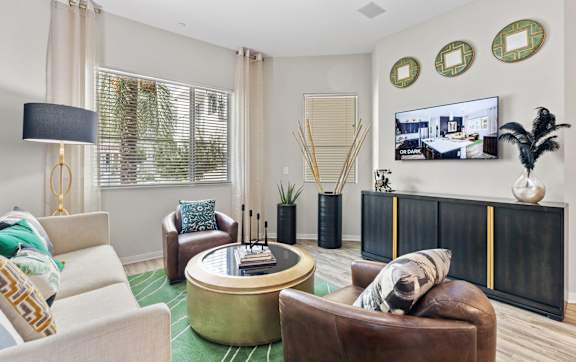 A living room with a white couch, a brown armchair, a coffee table, and a TV mounted on the wall.