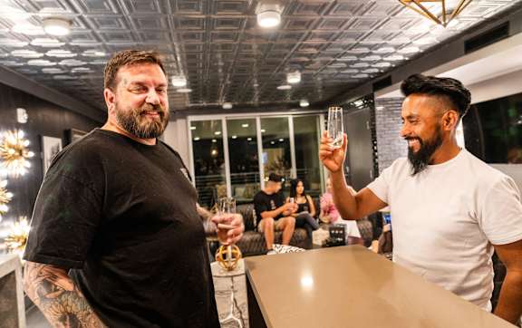 Two men toasting with drinks in a modern indoor setting.