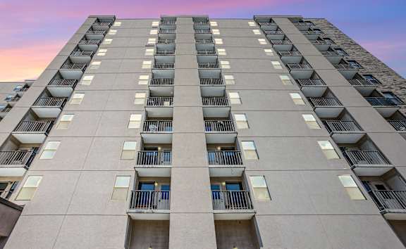 A tall residential building with balconies on each floor.