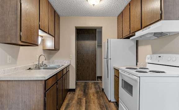 A kitchen with white appliances and wooden cabinets.