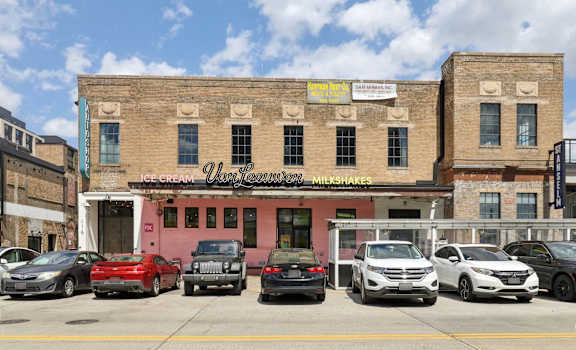 A row of cars parked in front of a building with a sign that says Ice Cream.