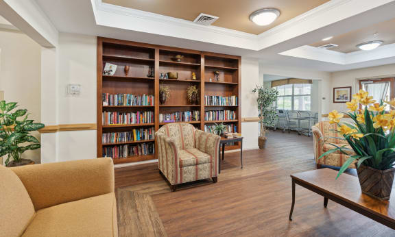 a seating area with couches and chairs and a bookshelf with books