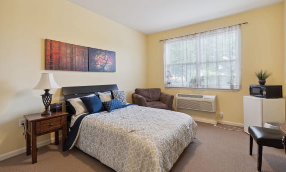 a bedroom with a bed and a chair in front of a window