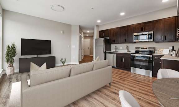 A modern living room with a couch, television, and kitchen area.