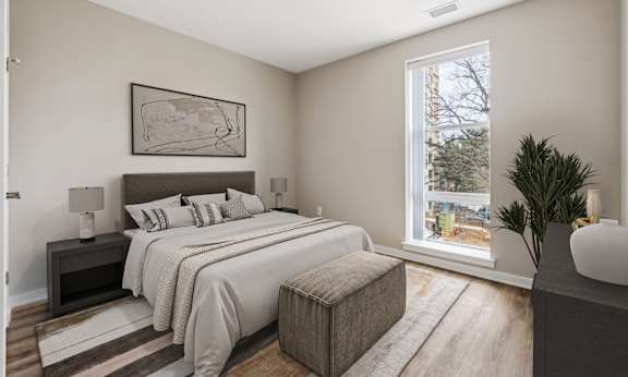 A bedroom with a large bed and a window overlooking a tree-lined street.