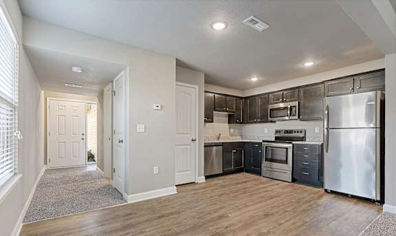 A kitchen with stainless steel appliances and wooden floors.