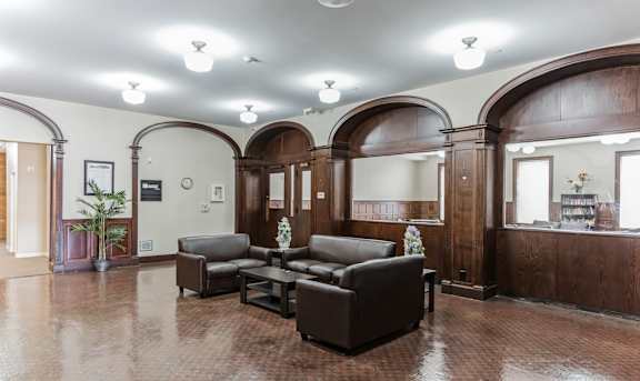 A living room with brown leather furniture and arched wooden doors at 13 State Street Apartments in Schenectady, NY