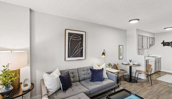 A living room with a grey couch, a coffee table, and a painting on the wall.