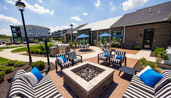 A patio with black and white striped couches and a fire pit.