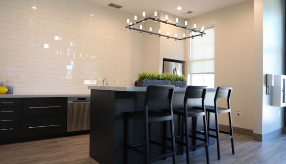 a kitchen with white tiles and a black island with black stools at St. Charles at Olde Court Apartments, Pikesville, MD