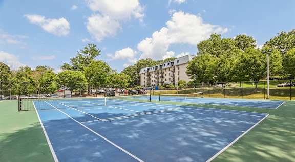 A tennis court surrounded by trees and buildings.