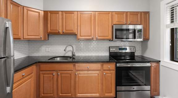 A kitchen with wooden cabinets and a black countertop.