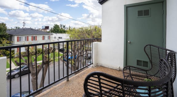 a balcony with a green door and two chairs on it
