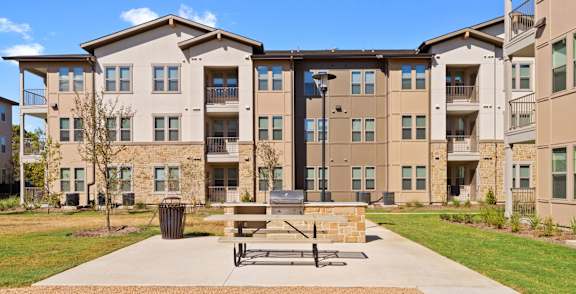 an outdoor patio with a picnic table in front of an apartment building