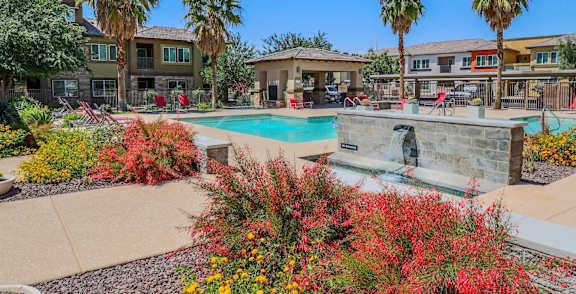A pool surrounded by palm trees and a building.