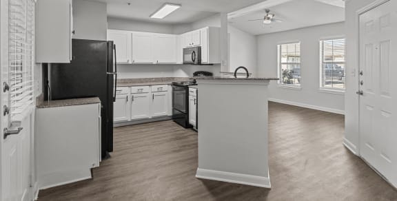 an open kitchen and living room with white cabinets and black appliances