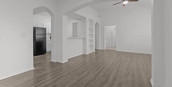 A spacious room with wooden flooring and white walls.