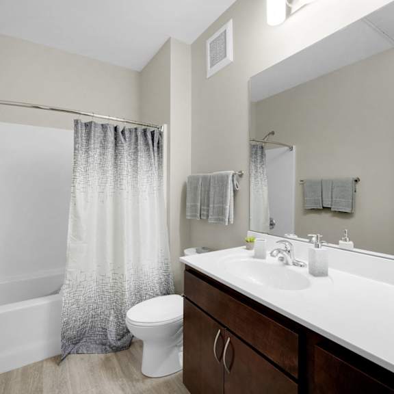 A bathroom with a white sink, toilet, and bathtub with a grey shower curtain.