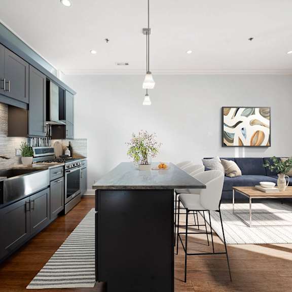A modern kitchen with dark grey cabinets and a black island.