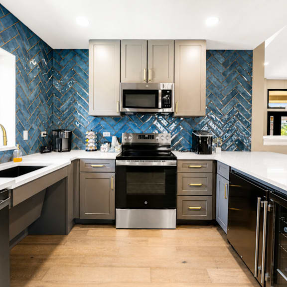 A modern kitchen with a blue tile backsplash and stainless steel appliances.