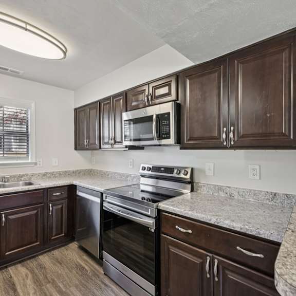 A kitchen with dark wood cabinets and stainless steel appliances.