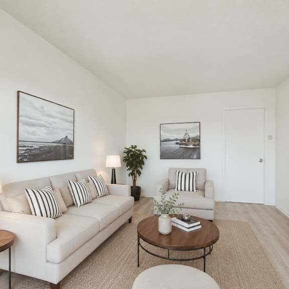 A living room with a white couch, a coffee table, a side table, and a television.