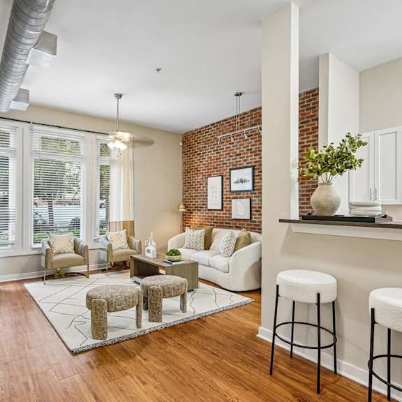 A living room with a white couch and a brick wall.