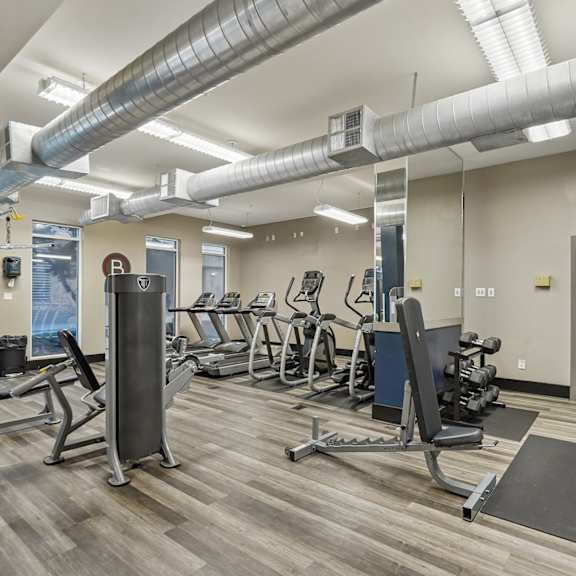 A gym with a variety of equipment including treadmills, weights, and exercise machines.