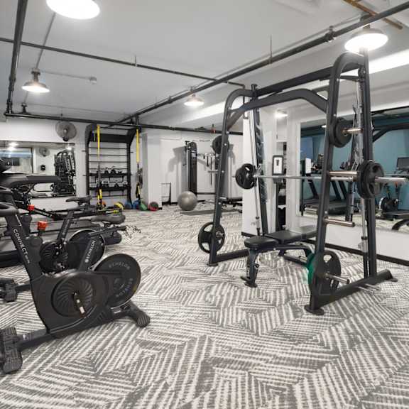 A gym with a variety of exercise equipment including a stationary bike, a rowing machine, and a weight bench.