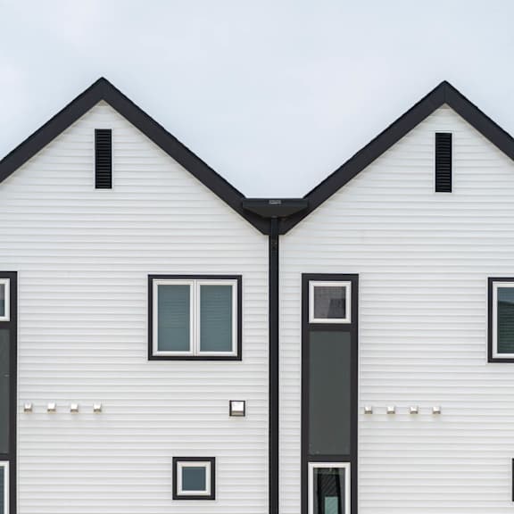 Three identical white houses with black trim and windows.