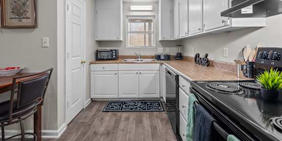 A kitchen with white cabinets and a black stove top.