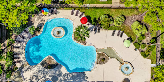 An aerial view of a swimming pool surrounded by trees and a playground.