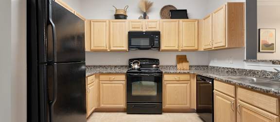 A kitchen with black appliances and wooden cabinets. at Stone Gate Apartments, North Carolina, 28390