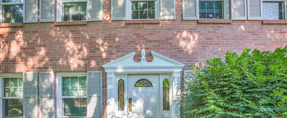 A white door with a small window above it is set in a brick wall.