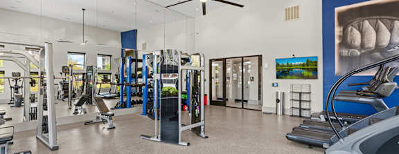 A spacious gym with treadmills, elliptical machines, and a fan.