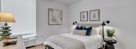A bedroom with a bed, a ceiling fan, and two wall lamps.