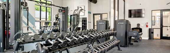A woman is doing squats on a box in a gym.