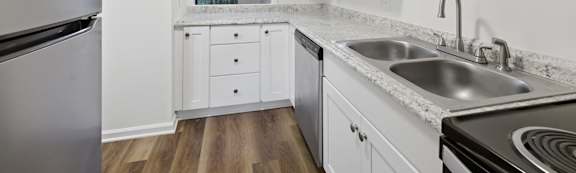 A kitchen with white cabinets and a stainless steel refrigerator.