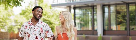 A man and a woman are walking together in front of a building with the word "AMERSON" on it.
