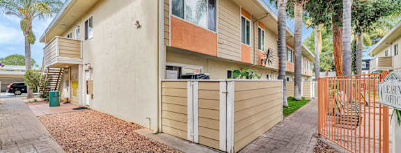 A beige house with a brown roof and a brown fence.