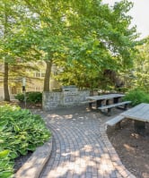 a picnic table and benches in a park with trees a picnic table and benches in a park with trees at Cumberland Crossing, Cumberland, 02864