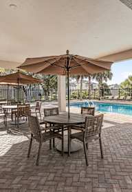 A patio with a table and chairs under an umbrella. at Cascades at Clear Lake Apartments, Florida