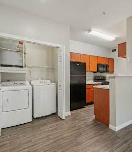 A living space with a kitchen and wood floors and washer and dryer
