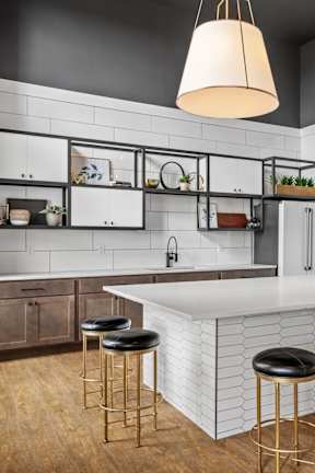 A kitchen with a white countertop and a bar stool.