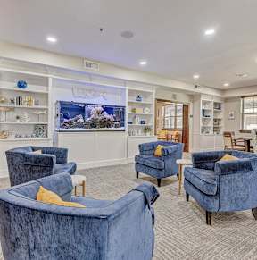 the lobby of a spa with blue chairs and a fish tank