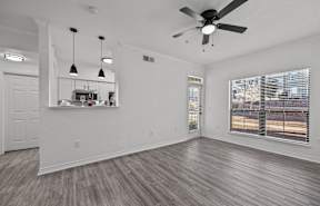 an empty living room with a ceiling fan and a window